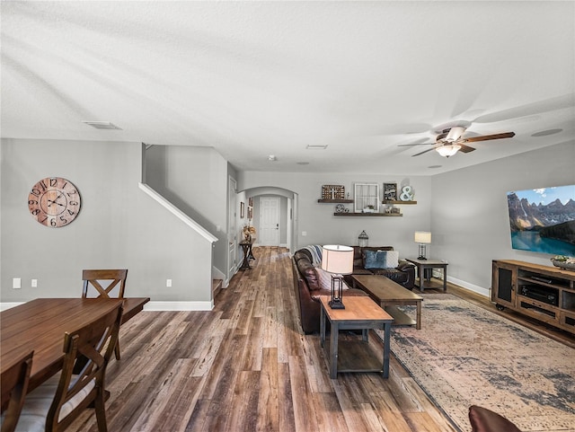 living area with wood finished floors, baseboards, visible vents, arched walkways, and ceiling fan