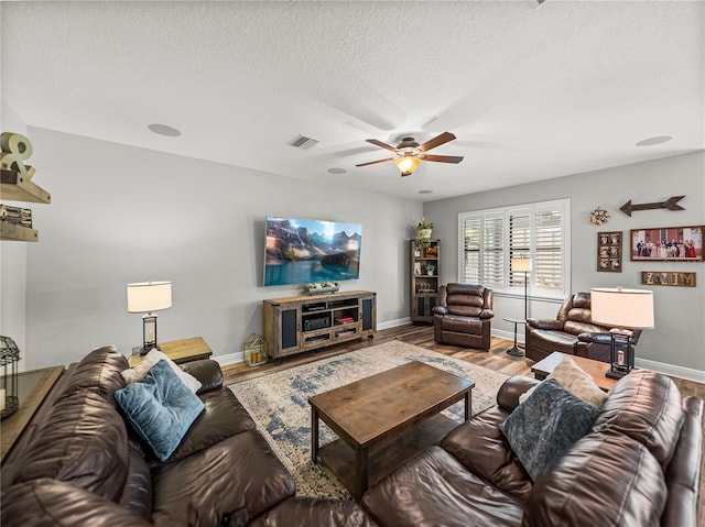 living area with visible vents, baseboards, wood finished floors, and a ceiling fan