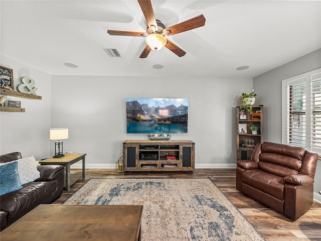 living area with visible vents, baseboards, ceiling fan, and wood finished floors