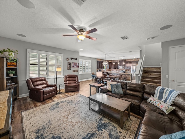 living room with visible vents, wood finished floors, a ceiling fan, and stairway