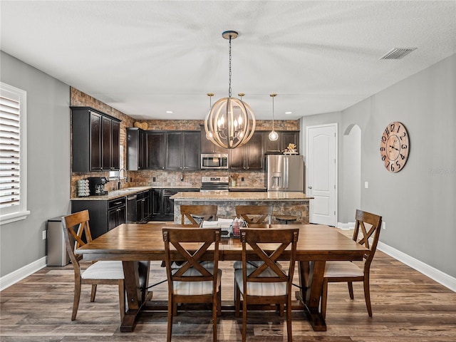 dining room featuring visible vents, a notable chandelier, dark wood-style floors, arched walkways, and baseboards