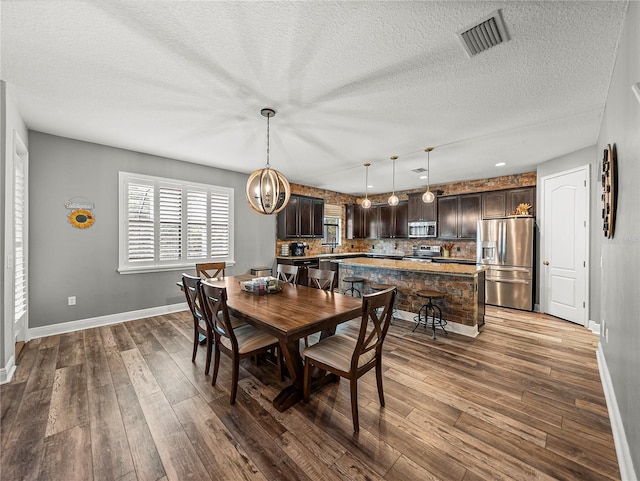 dining area featuring visible vents, baseboards, a chandelier, a textured ceiling, and dark wood-style flooring