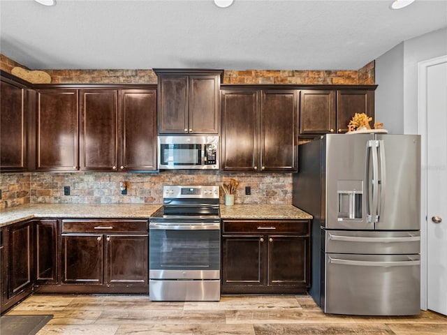 kitchen with stainless steel appliances, dark brown cabinets, light wood-style flooring, and decorative backsplash