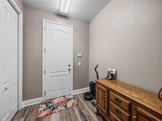 foyer entrance with baseboards, a textured ceiling, and dark wood-style flooring