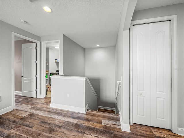 stairway with recessed lighting, wood finished floors, baseboards, and a textured ceiling