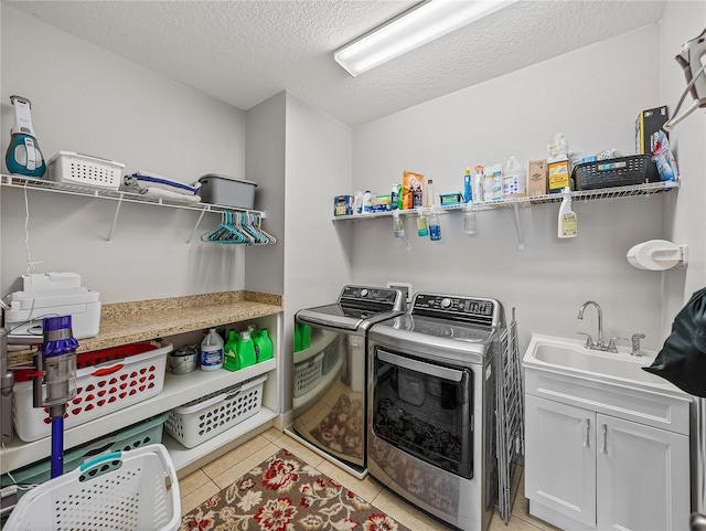 laundry area with a sink, a textured ceiling, washing machine and dryer, light tile patterned floors, and laundry area