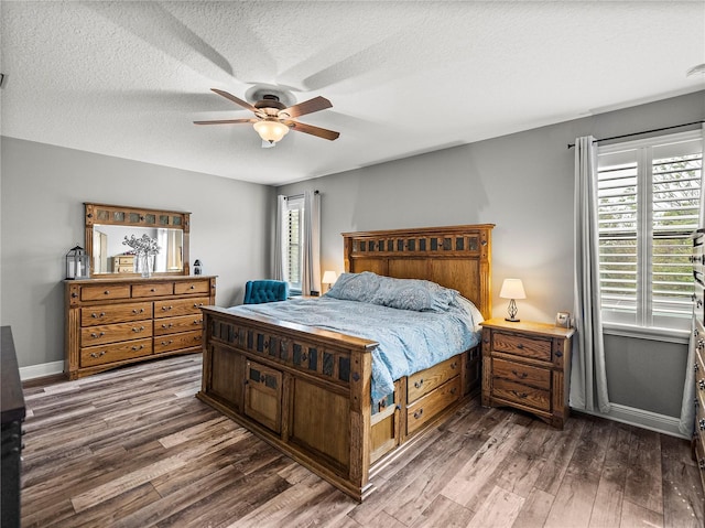 bedroom with ceiling fan, dark wood-type flooring, baseboards, and a textured ceiling