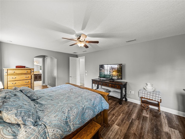 bedroom featuring visible vents, a textured ceiling, wood finished floors, arched walkways, and baseboards