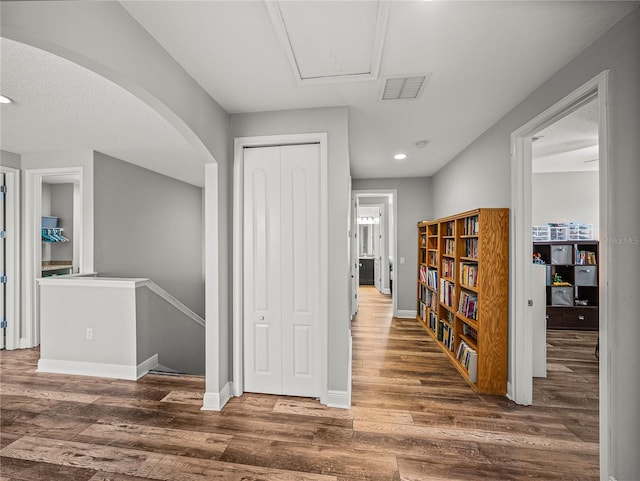 hallway featuring wood finished floors, attic access, an upstairs landing, and baseboards