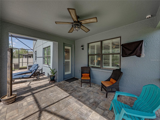 view of patio / terrace featuring a lanai, a ceiling fan, and fence