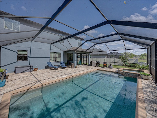 view of pool with glass enclosure, a pool with connected hot tub, and a patio