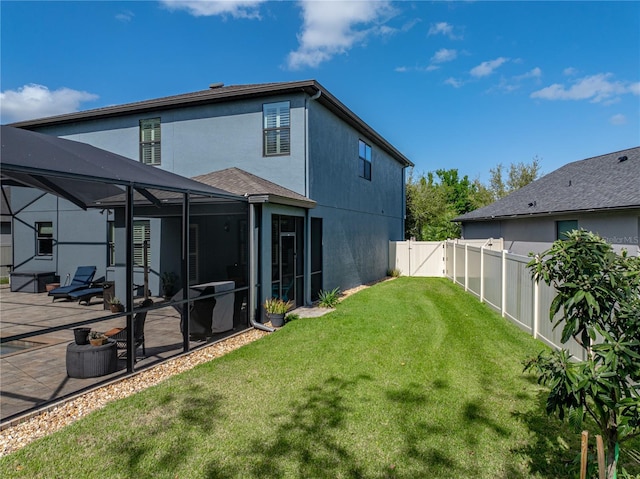 rear view of property featuring glass enclosure, a yard, a fenced backyard, a patio area, and a gate