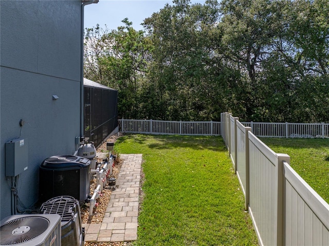 view of yard featuring glass enclosure, central AC, and a fenced backyard