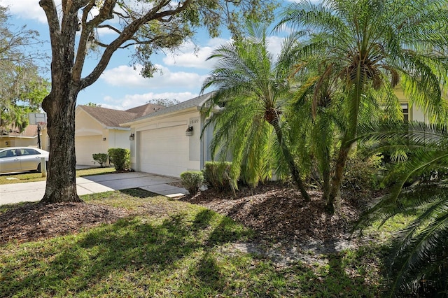 view of side of property with concrete driveway, a garage, and stucco siding