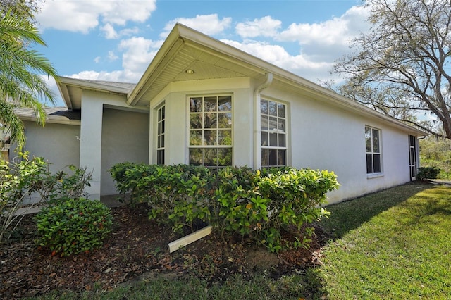 view of property exterior with a lawn and stucco siding