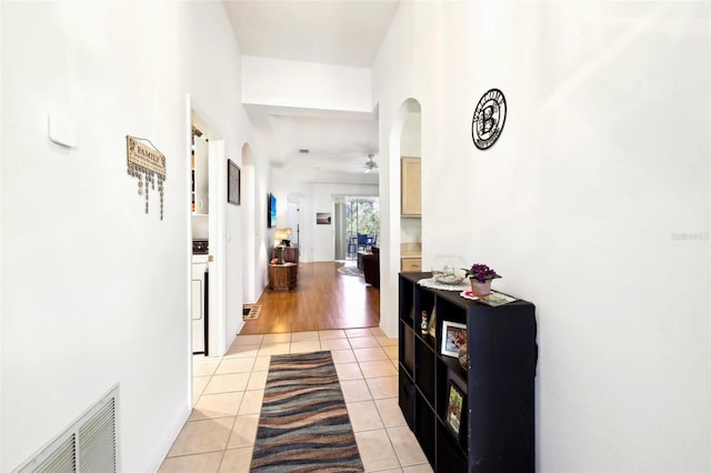 hall featuring visible vents, arched walkways, light tile patterned flooring, and washer / clothes dryer