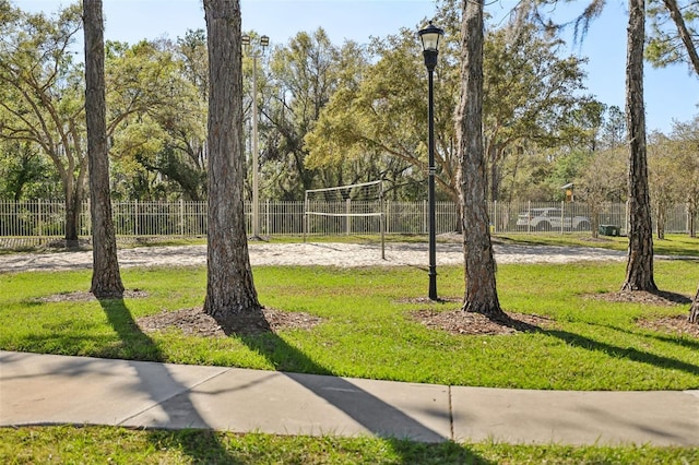 view of home's community featuring a yard, fence, and volleyball court