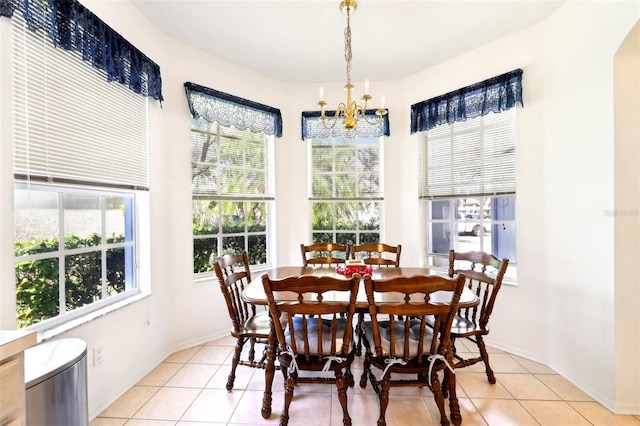 dining space featuring light tile patterned floors, a notable chandelier, and baseboards