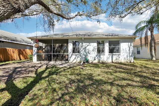 back of house with a yard, a sunroom, stucco siding, and fence