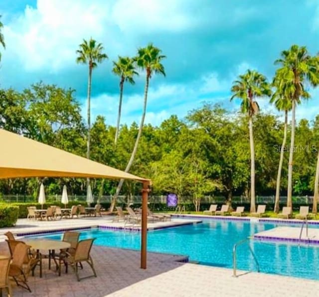 community pool with a patio and fence