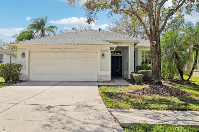 single story home with concrete driveway, an attached garage, roof with shingles, and stucco siding