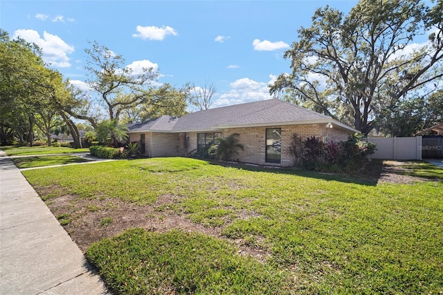 view of front of house with brick siding, a front lawn, and fence