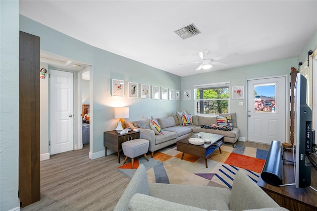 living room with ceiling fan, visible vents, baseboards, and wood finished floors