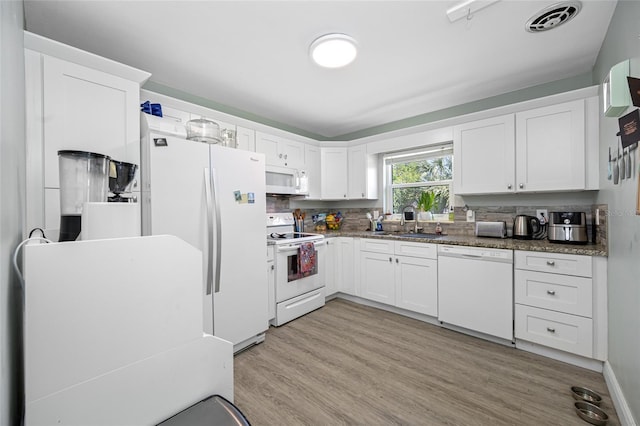 kitchen featuring visible vents, a sink, white cabinetry, white appliances, and light wood finished floors