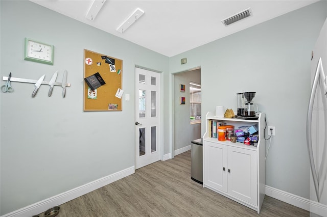 interior space featuring visible vents, light wood-style flooring, and baseboards