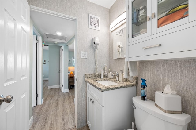 half bath featuring vanity, toilet, and wood finished floors