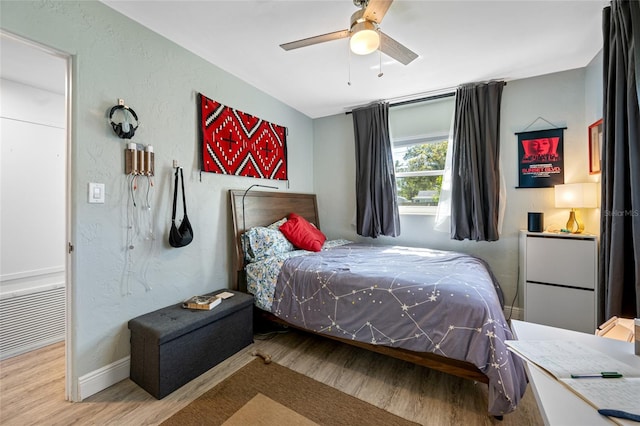 bedroom featuring wood finished floors, visible vents, and a textured wall