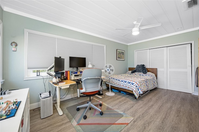 bedroom featuring visible vents, ceiling fan, ornamental molding, wood finished floors, and a closet