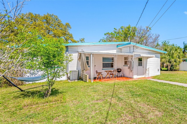 rear view of house with central AC unit, a lawn, and a porch