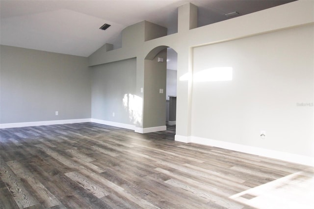 unfurnished room with visible vents, dark wood-type flooring, baseboards, arched walkways, and high vaulted ceiling