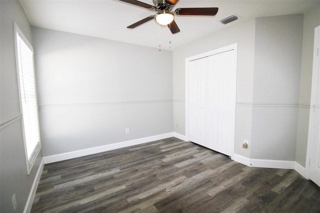 unfurnished bedroom featuring wood finished floors, visible vents, baseboards, ceiling fan, and a closet