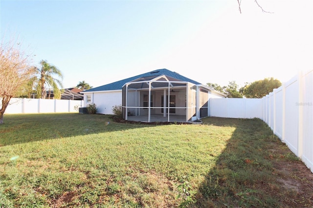 rear view of house with a lawn, a fenced backyard, and a sunroom