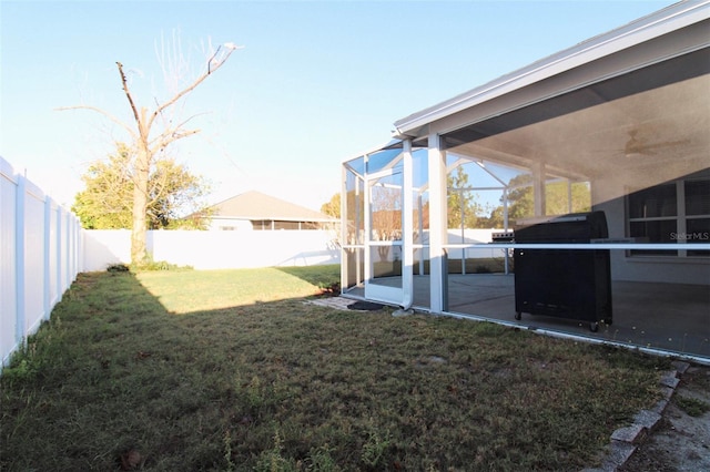 view of yard with glass enclosure, a fenced backyard, and ceiling fan