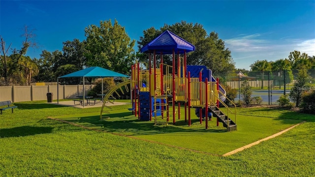 community play area featuring a yard and fence