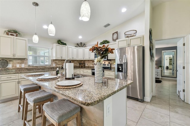 kitchen with visible vents, stainless steel appliances, decorative backsplash, and vaulted ceiling