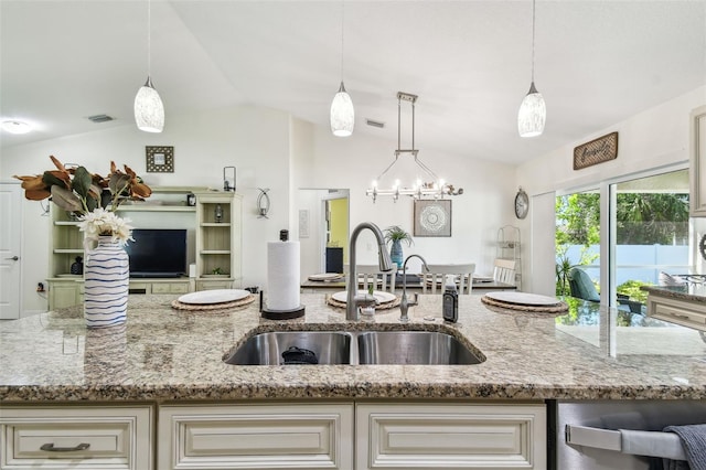 kitchen with a sink, visible vents, light stone counters, and open floor plan