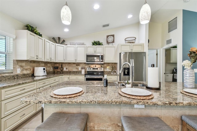 kitchen with a kitchen bar, vaulted ceiling, visible vents, and appliances with stainless steel finishes