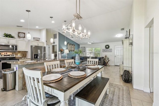 dining area with light tile patterned floors, visible vents, baseboards, and high vaulted ceiling