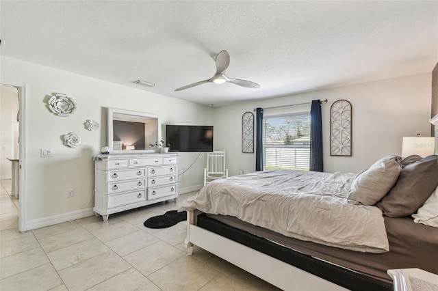 bedroom featuring visible vents, a ceiling fan, a textured ceiling, light tile patterned floors, and baseboards