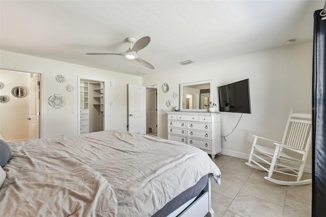 bedroom featuring visible vents, a walk in closet, light tile patterned flooring, baseboards, and ceiling fan