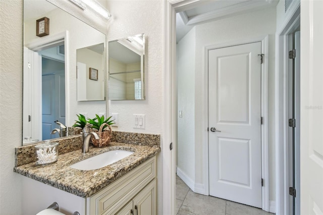 bathroom with tile patterned floors, vanity, and a textured wall