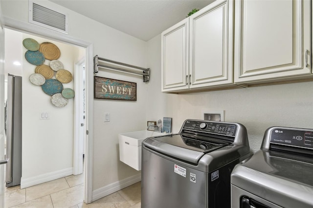 washroom featuring light tile patterned floors, visible vents, baseboards, cabinet space, and washer and dryer