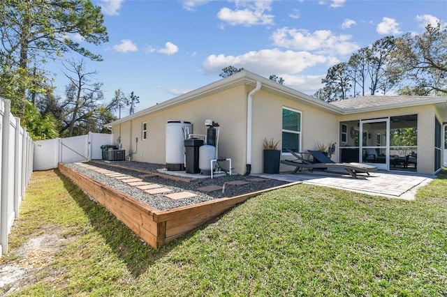 rear view of property featuring stucco siding, a lawn, a sunroom, a patio, and a gate