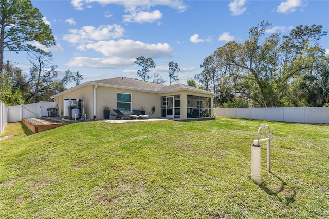 back of house with a yard, stucco siding, a fenced backyard, and a sunroom