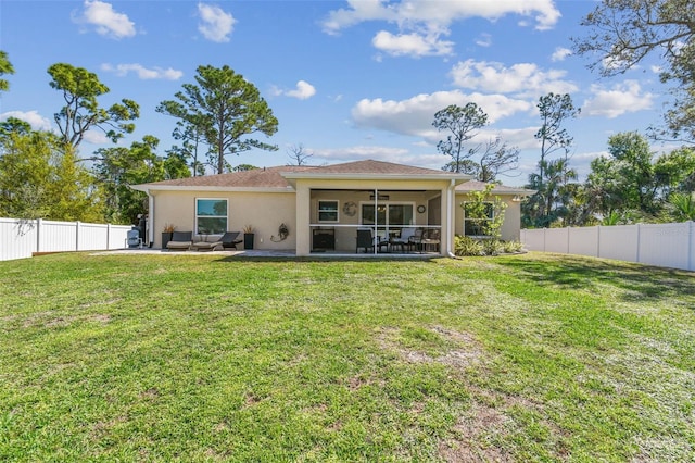 rear view of house featuring a patio, a yard, a fenced backyard, a sunroom, and stucco siding