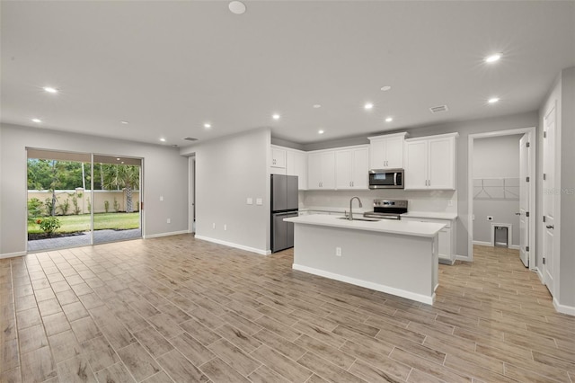 20405 Symphony Pl, Venice, FL 34293 - kitchen with white cabinets, a sink, open floor plan, light countertops, and appliances with stainless steel finishes
